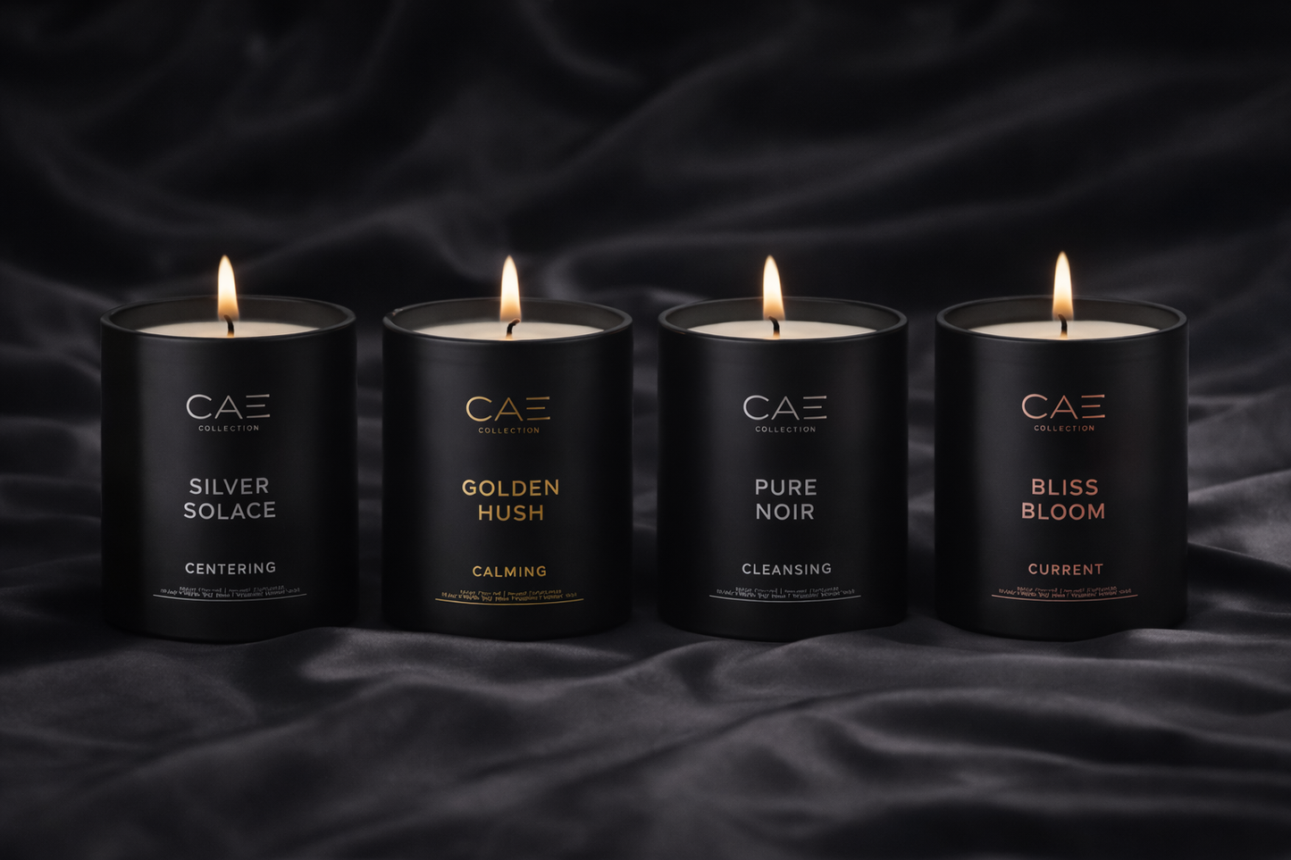 Four black candles with labels on a dark fabric background