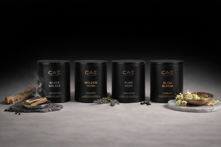 A row of four matte black candle vessels arranged on a light stone.